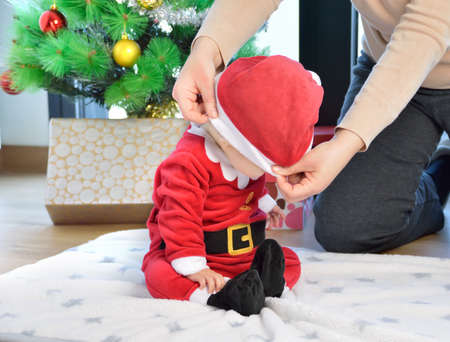 An excited baby at christmas time sitting next to a wrapped presentの写真素材