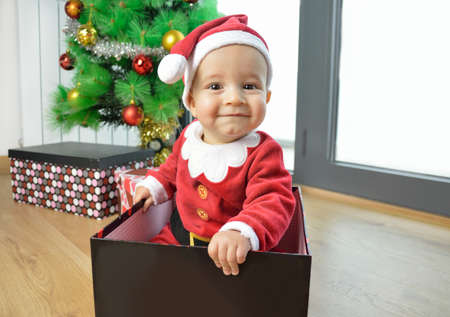 An excited baby at christmas time sitting next to a wrapped presentの写真素材