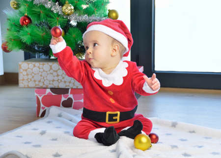 An excited baby at christmas time sitting next to a wrapped presentの写真素材