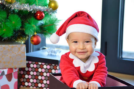 An excited baby at christmas time sitting next to a wrapped presentの写真素材