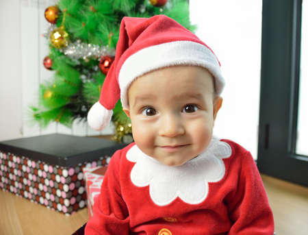 An excited baby at christmas time sitting next to a wrapped presentの写真素材