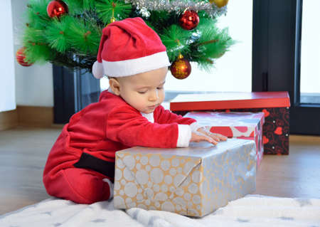 An excited baby at christmas time sitting next to a wrapped presentの写真素材