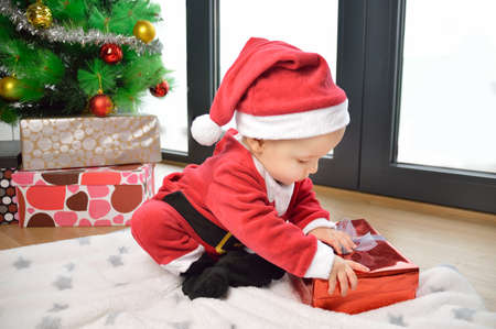 An excited baby at christmas time sitting next to a wrapped presentの写真素材