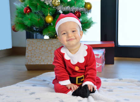 An excited baby at christmas time sitting next to a wrapped presentの写真素材