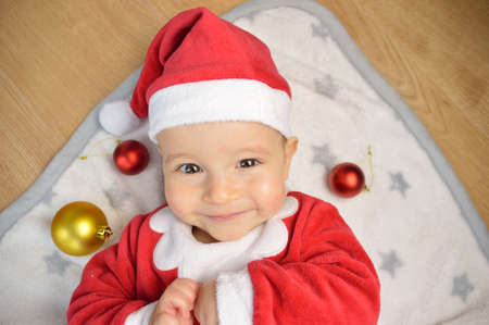 An excited baby at christmas time sitting next to a wrapped presentの写真素材
