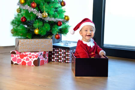 An excited baby at christmas time sitting next to a wrapped presentの写真素材