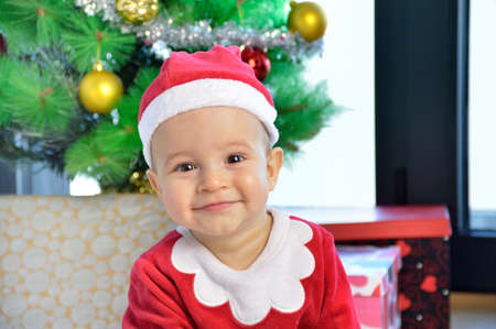 An excited baby at christmas time sitting next to a wrapped presentの写真素材