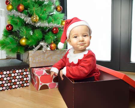An excited baby at christmas time sitting next to a wrapped presentの写真素材