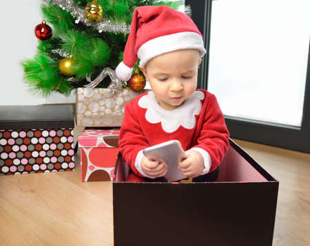 An excited baby at christmas time sitting next to a wrapped presentの写真素材