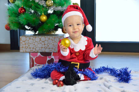 An excited baby at christmas time sitting next to a wrapped presentの写真素材