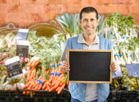 farmer holding an empty chalkboard at the vegetables storeの写真素材