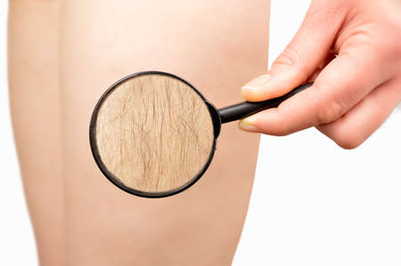 Woman looking with a magnifying glass if her leg is properly shavedの写真素材