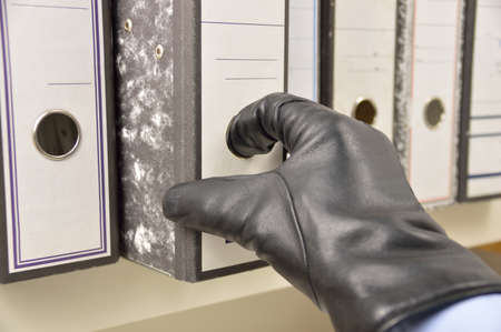 thief stealing ring binder and confidential files in an officeの写真素材