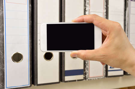 businessman taking photo of documents with smart phone in connection with industrial espionageの写真素材