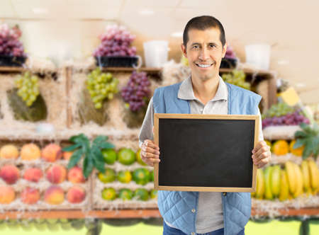 farmer holding an empty chalkboard at the fruits storeの写真素材