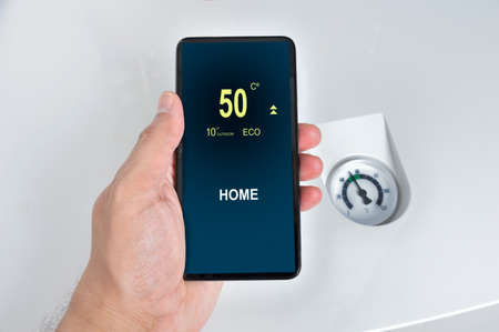 regulating the temperature from the smart phone and controlling the thermostat with finger pressing buttonの写真素材