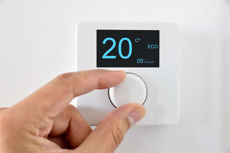 Man's hand adjust thermostat digital in celsius at homeの写真素材