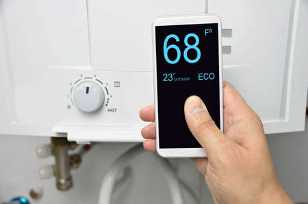 Man adjusting burner temperature with a phoneの写真素材