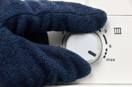 Man's hand rotate temperature adjuster of water heater. High tempの写真素材