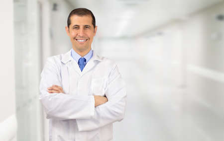 A handsome doctor standing with his arms folded and smiling at the cameraの写真素材