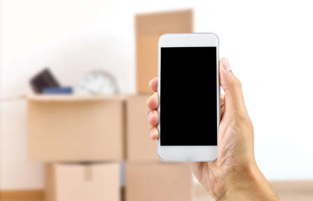 Unrecognizable person moving house and using an app on a cell phoneの写真素材