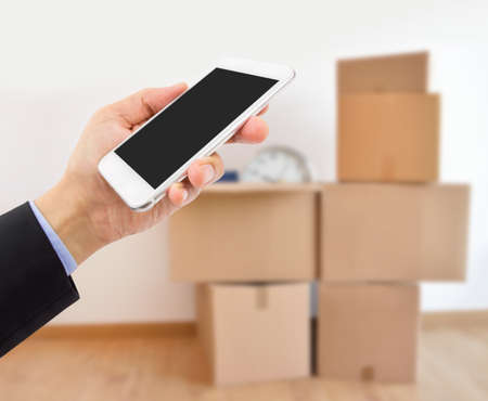 Unrecognizable business person moving office and using an app on a cell phoneの写真素材