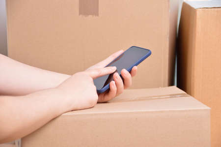 Closeup shot of an unidentifiable delivery woman using a smart phoneの写真素材