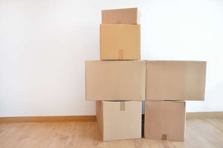 Moving in. Stack of cardboard boxes in the empty room with copy spaceの写真素材