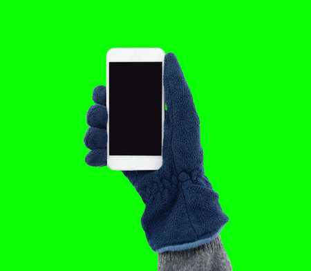 hand with glove holding a smart phone  in winter and isolated cutout on green background with chroma keyの写真素材