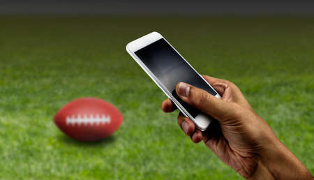 betting man through his smart phone in at stadiumの写真素材