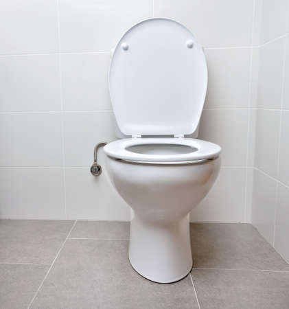 White toilet bowl in a bathroom with the lid openの写真素材