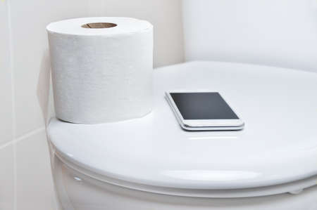 close up of toilet and a phone to work from the toilet and forgottenの写真素材