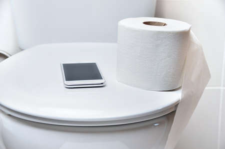 close up of toilet and a phone to work from the toilet and forgottenの写真素材