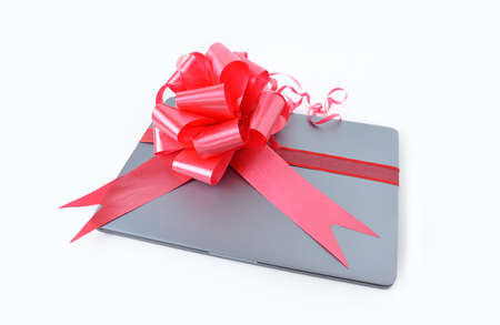 Close-up of laptop gift with a red ribbonの写真素材