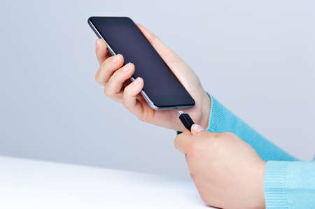 Woman hands plugging a charger in a smart phoneの写真素材