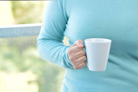 Woman hands holding a coffee mug at homeの写真素材