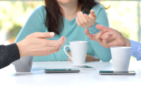 Three friends hands talking in a bar and disconnected from social networks with the phone on the tableの写真素材