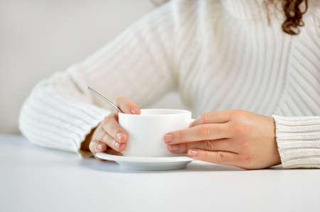 Closeup shot of an unrecognizable woman having a cup of coffee at a cafeの写真素材