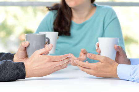 Three friends talking and holding coffee cupsの写真素材