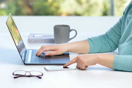 Woman hands using a smart phone and laptop