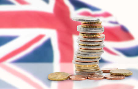 Coins stacked on each other in different positions with United kingdom flagの写真素材