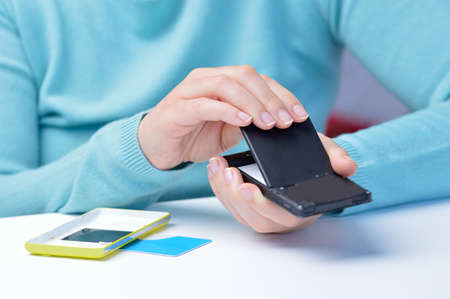 Woman hand putting a battery into a smart phoneの写真素材