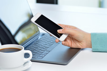 Close up of girl hands using a smart phone and laptop