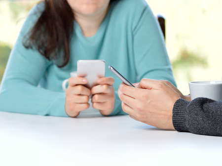 Two friends using their smart phones in a barの写真素材