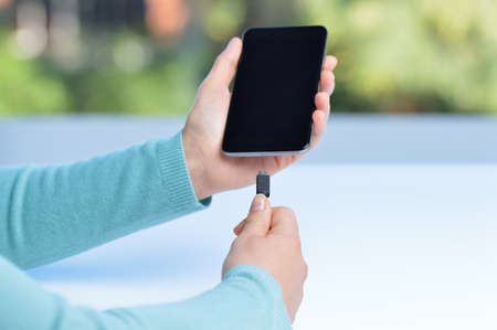 Woman hands plugging a charger in a smart phoneの写真素材