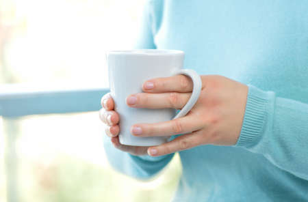 Woman hands holding a coffee mug at homeの写真素材