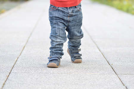 Cropped image of the legs of a baby walking at streetの写真素材