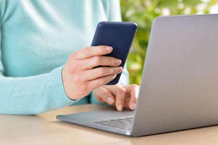 Close up of a woman hand using a blue smart phone on a desk at homeの写真素材