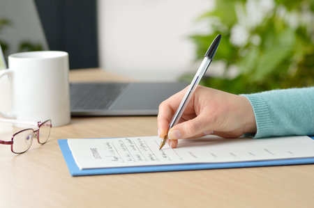 Close up of a woman hand filling form on a table