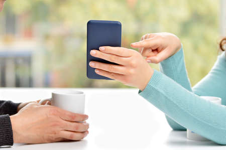 Close up of couple hands using a smartphone and showingの写真素材